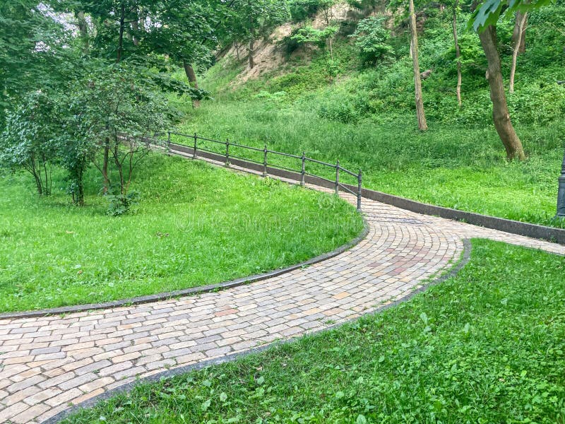 Large, diagonal brick path in a lush green park under soft afternoon lighting No visible texts or signs t. Elegant lighting signs stock images, royalty-free photos and pictures