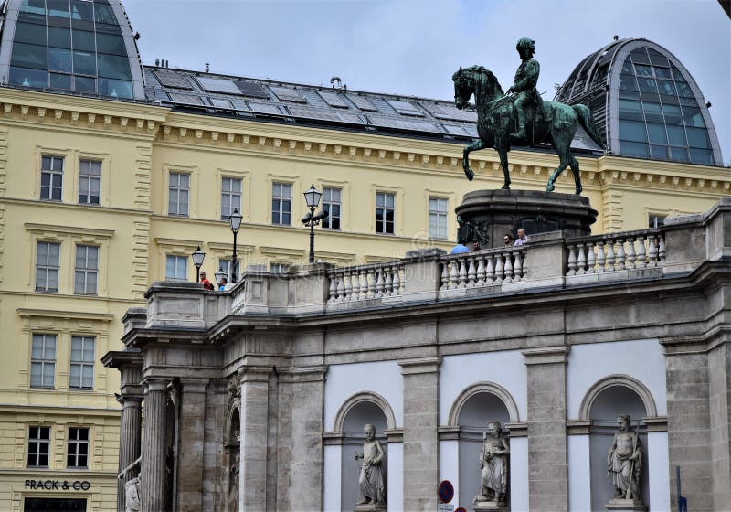 Large equestrian statue in Vienna. In the foreground the facade of a bridge with three statues and in the background a historic bu stock image Large equestrian statue in Vienna. In the foreground the facade of a bridge with three statues and in the background a historic bu stock image
