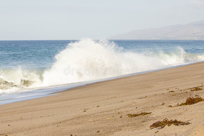 Large exploding splashing spray from wave on sandy beach, with open ocean expanse royalty free stock image Large exploding splashing spray from wave on sandy beach, with open ocean expanse royalty free stock image