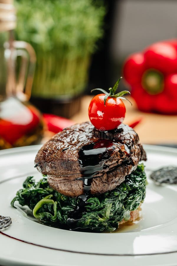 Large Grilled Filet Mignon Steak with Spinach. Grilled Meat Dish with