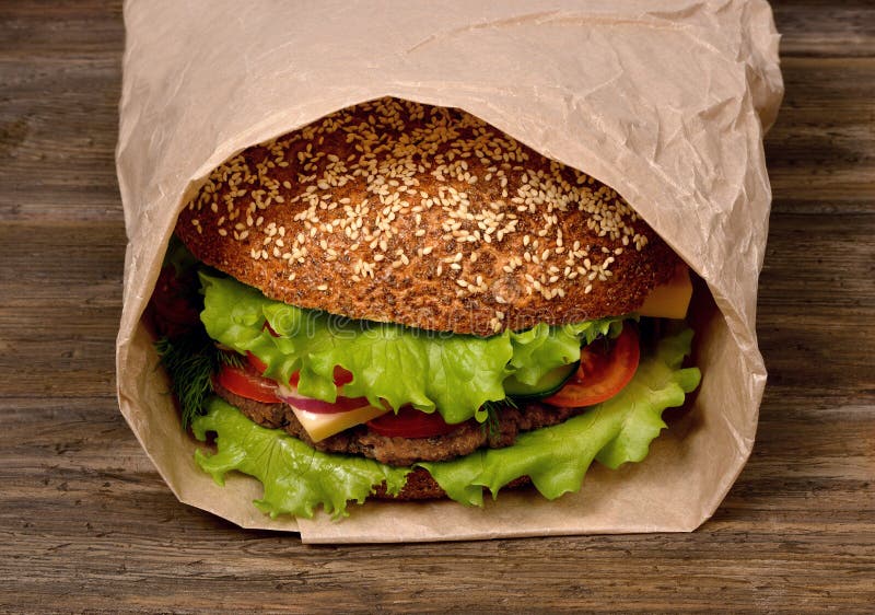 Large hamburger on a wooden table is packed in a paper bag royalty free stock photos Large hamburger on a wooden table is packed in a paper bag royalty free stock photos