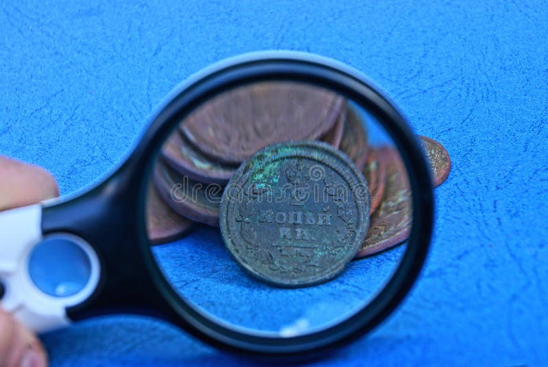Magnifier and a Bunch of Old Copper Coins on a Blue Table Stock Image