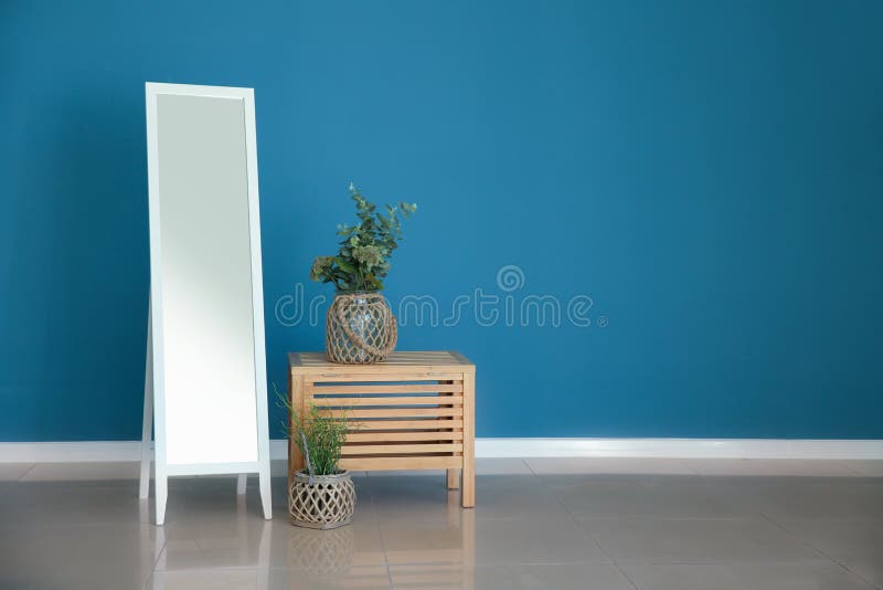 Large mirror, table and houseplants near color wall