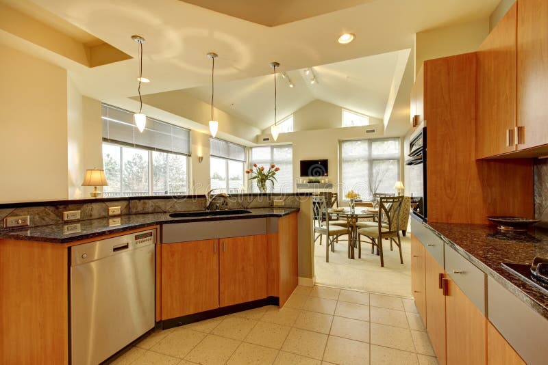 Large modern wood kitchen with living room and high ceiling.