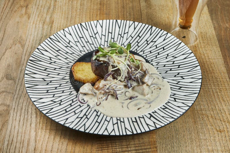 Large portion of delicious beef steak with creamy mushroom sauce and fried potatoes in a ceramic plate on a wooden background royalty free stock photos Large portion of delicious beef steak with creamy mushroom sauce and fried potatoes in a ceramic plate on a wooden background royalty free stock photos
