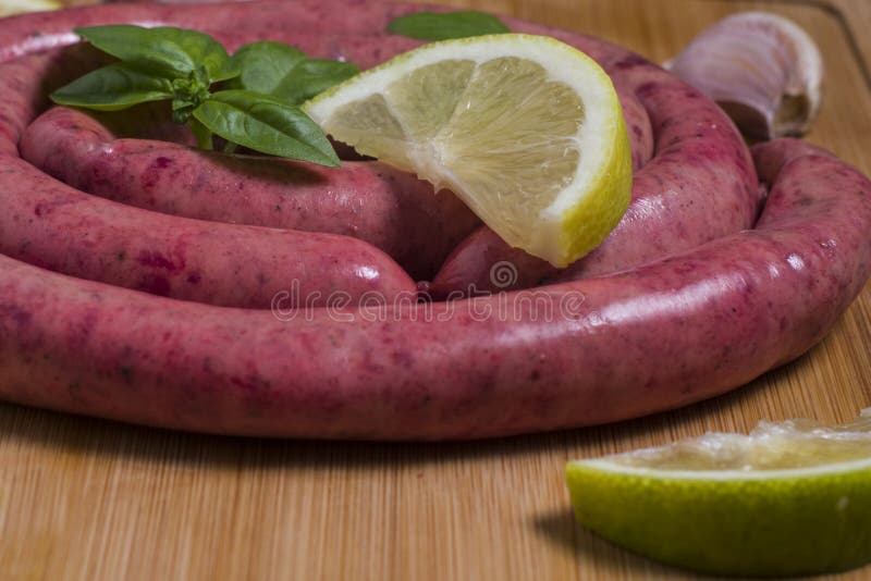 A Large Raw Argentinian Sausage with Some Slice of Lemon and Basil