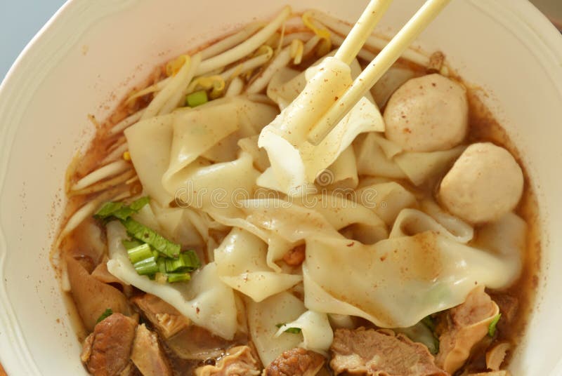 Large Rice Noodle with Braised Pork in Soup Picking by Chopsticks Stock