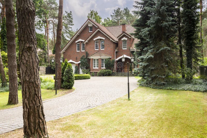 Large, rural estate with brick facade and green lawn standing in