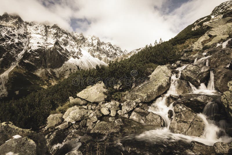 Veľký vodopád z rokliny na jeseň, dlhá expozícia s horami v pozadí - vzhľad vintage filmu