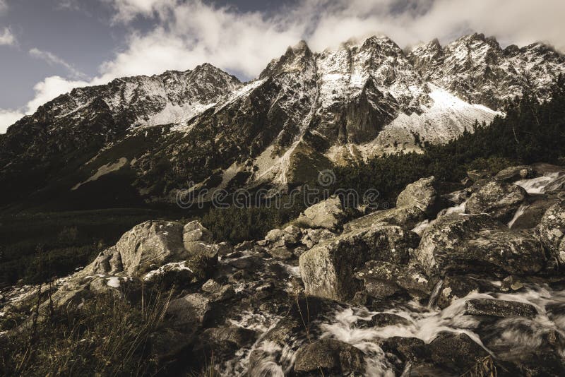 Large Waterfall from ravine in autumn, long exposure with mountains in background - vintage film look