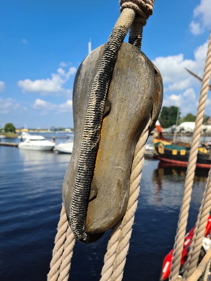 Large wooden blocks are attached to different ropes of a large sailing vessel.