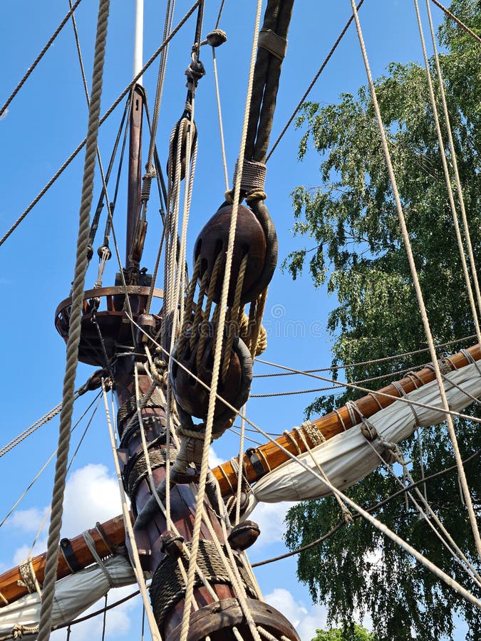 Large wooden blocks are attached to different ropes of a large sailing vessel.