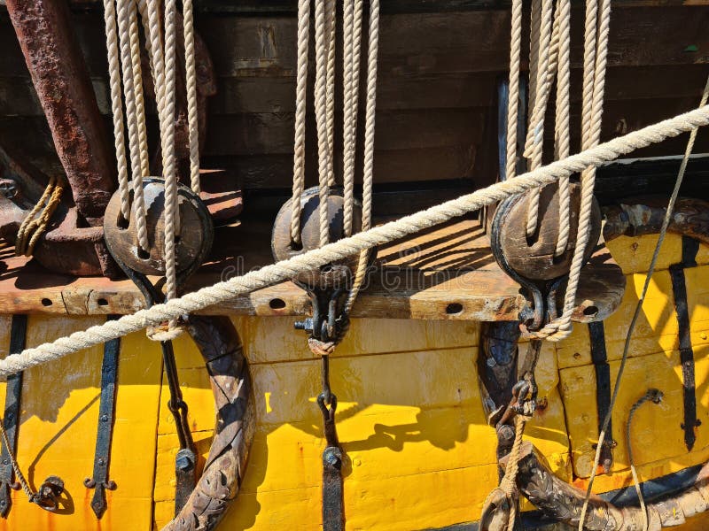 Large wooden blocks are attached to different ropes of a large sailing vessel.