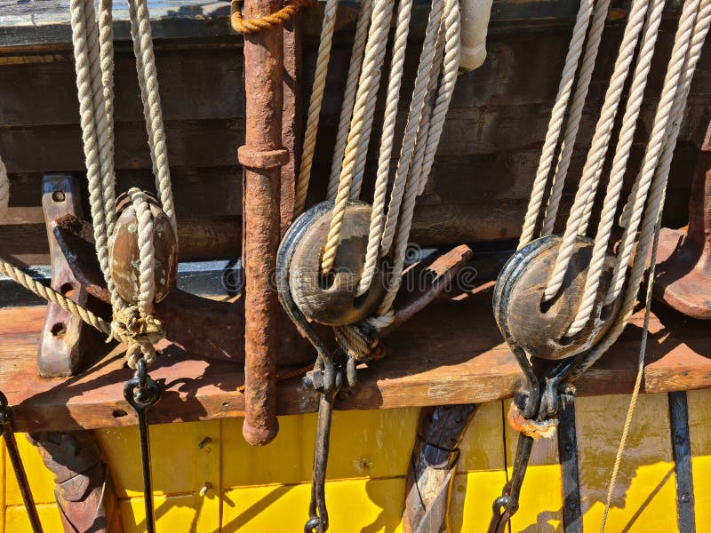 Large wooden blocks are attached to different ropes of a large sailing vessel.