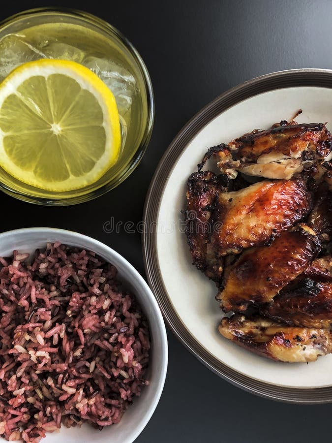 Las alas de pollo frito del aire en plato de cerámica sirven con el pequeño cuenco de Riceberry cocinado y un vidrio de té verde fotos de archivo libres de regalías Las alas de pollo frito del aire en plato de cerámica sirven con el pequeño cuenco de Riceberry cocinado y un vidrio de té verde fotos de archivo libres de regalías