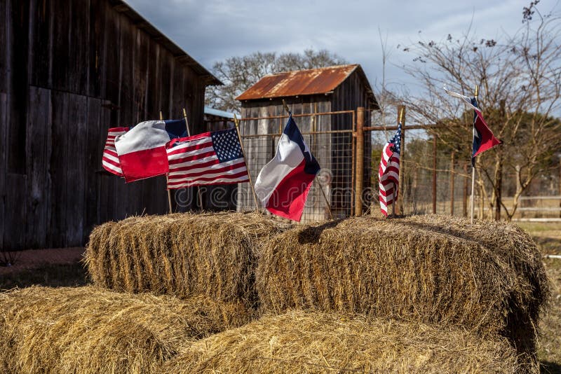 Las banderas del americano y de Tejas arreglaron en las balas de la paja, decoración del Día de la Independencia imagen de archivo Las banderas del americano y de Tejas arreglaron en las balas de la paja, decoración del Día de la Independencia imagen de archivo