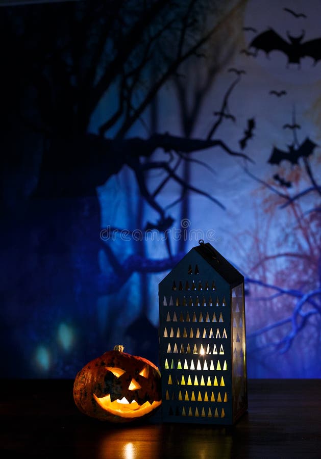 Las calabazas anaranjadas con las caras, la linterna y las velas asustadizas mienten en la tabla delante del fondo azul marino Ce imagen de archivo libre de regalías Las calabazas anaranjadas con las caras, la linterna y las velas asustadizas mienten en la tabla delante del fondo azul marino Ce imagen de archivo libre de regalías