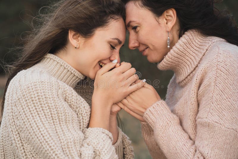 Las chicas están congeladas para caminar y calentando sus manos. una amiga le da el brazo. cierre de las manos de dos niñas. La chica calienta las manos de sus amigos. una mujer en un suéter con un tejido grande está congelada y se calienta. cierre de las palmas de las niñas que abrigan las manos. foto de alta calidad