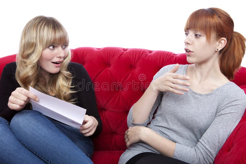 Las Chicas Jóvenes En El Sofá Rojo Son Emocionadas Imagen de archivo