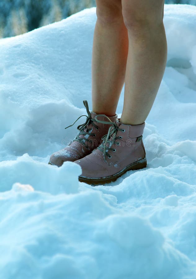 The girl's bare leg in fashionable boots turned blue on a frosty snow day. Women as fashion victims. The girl's bare leg in fashionable boots turned blue on a frosty snow day. Women as fashion victims