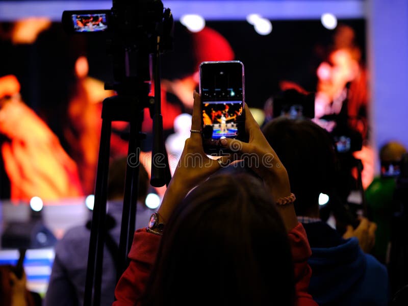 Las chicas usan smartphones para tomar fotos en conciertos imagen de archivo Las chicas usan smartphones para tomar fotos en conciertos imagen de archivo