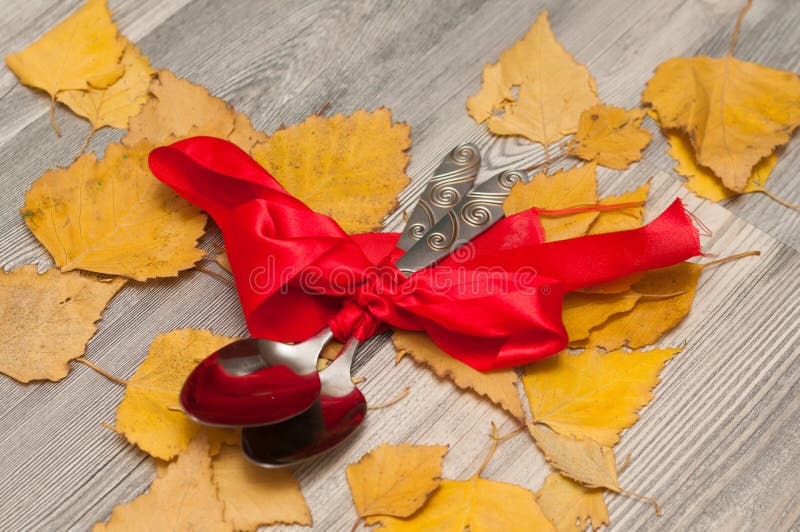 Las cucharas se envuelven en una cinta roja con un arco como regalo en el fondo fotos de archivo Las cucharas se envuelven en una cinta roja con un arco como regalo en el fondo fotos de archivo