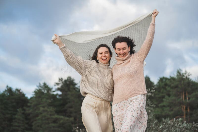 Las dos mujeres más felices disfrutan de la vida y miren a la distancia. chicas con sudaderas ligeras con un tejido grande. gentil fotografía de archivo
