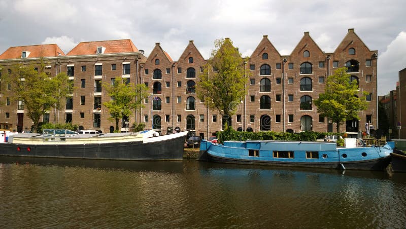 Las fachadas de las casas y de los barcos a lo largo de la costa en Amsterdam imágenes de archivo libres de regalías Las fachadas de las casas y de los barcos a lo largo de la costa en Amsterdam imágenes de archivo libres de regalías