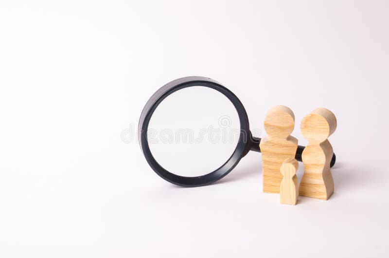 Wooden figures of people stand near the magnifying glass. The family is looking for something. The concept of housing search. Marketing, management. Human resources, social unit and statistics. Wooden figures of people stand near the magnifying glass. The family is looking for something. The concept of housing search. Marketing, management. Human resources, social unit and statistics.