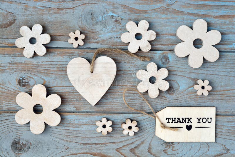 Wooden white wash flowers, heart, black chalk board and thank you label on a blue grey knotted old wooden background with empty space layout. Wooden white wash flowers, heart, black chalk board and thank you label on a blue grey knotted old wooden background with empty space layout