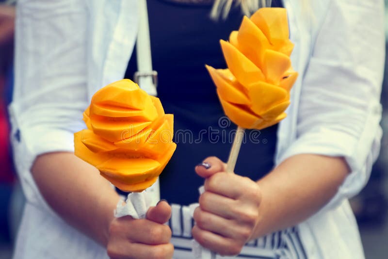 Las frutas de un mango maduro jugoso bajo la forma de flores en las manos de una chica joven Comida de la calle de México fotografía de archivo libre de regalías
