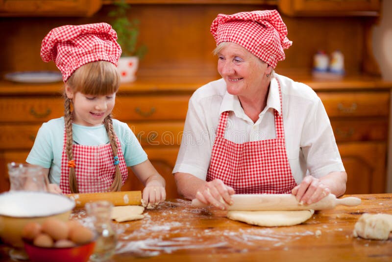 Las galletas de la hornada de la abuela y de la nieta preparan la pasta foto de archivo libre de regalías Las galletas de la hornada de la abuela y de la nieta preparan la pasta foto de archivo libre de regalías