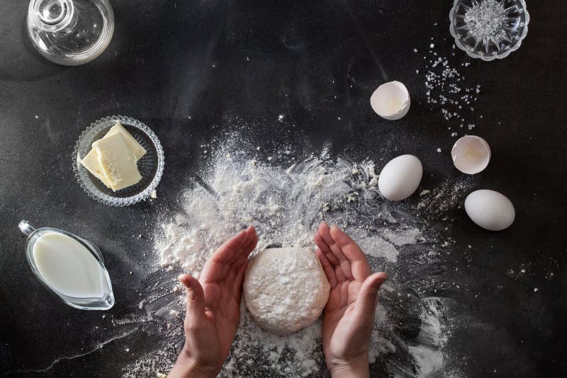 Las manos de la mujer amasan la pasta en la tabla con la harina fotos de archivo libres de regalías Las manos de la mujer amasan la pasta en la tabla con la harina fotos de archivo libres de regalías