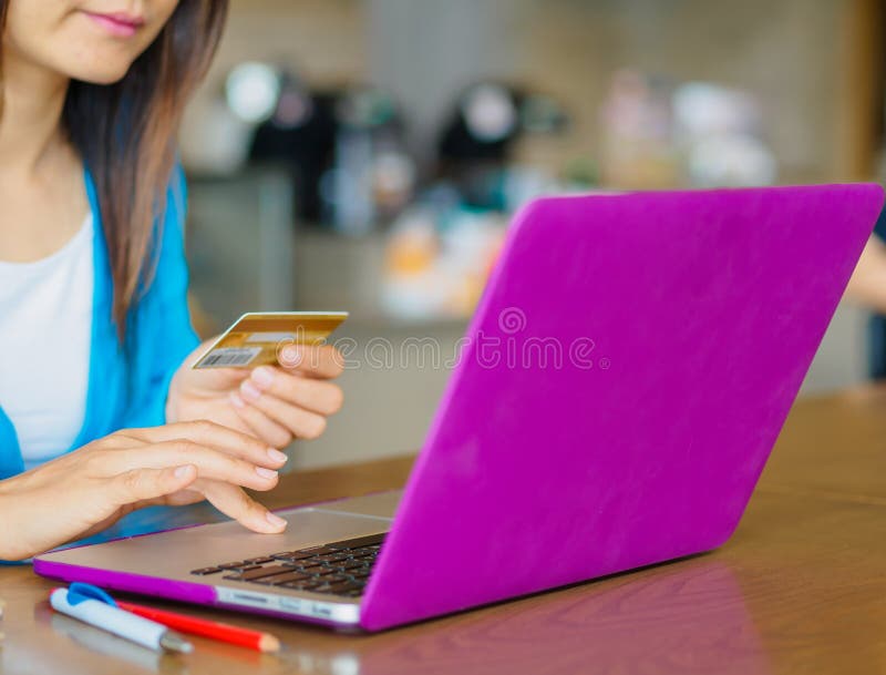 Las manos de la mujer bastante joven que sostienen una tarjeta de crédito y que usan el ordenador portátil para las compras en lí imagen de archivo Las manos de la mujer bastante joven que sostienen una tarjeta de crédito y que usan el ordenador portátil para las compras en lí imagen de archivo