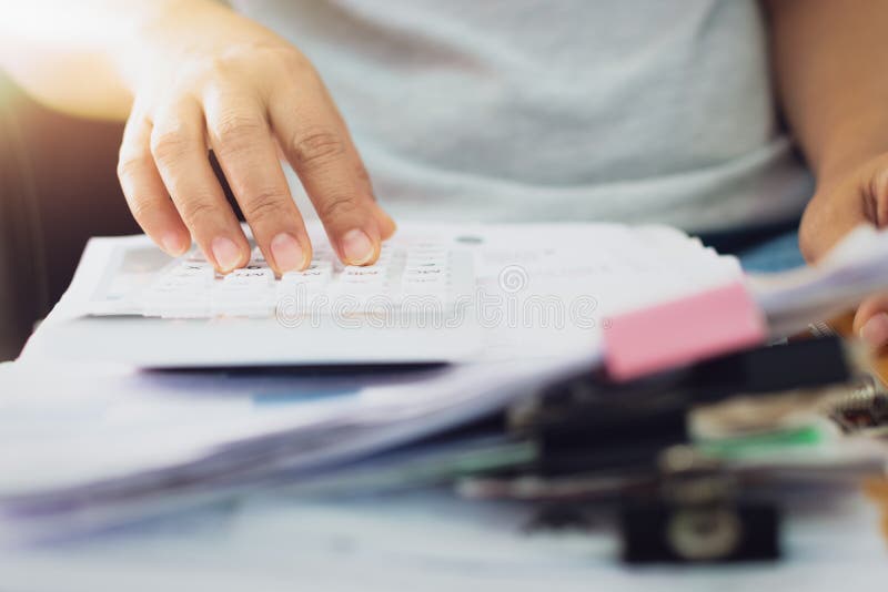 Las manos de la mujer están calculando documentos de los costos en casa foto de archivo libre de regalías Las manos de la mujer están calculando documentos de los costos en casa foto de archivo libre de regalías