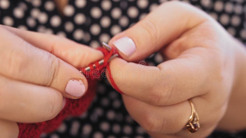 Las manos de la mujer tejen agujas de punto de hilados rojos