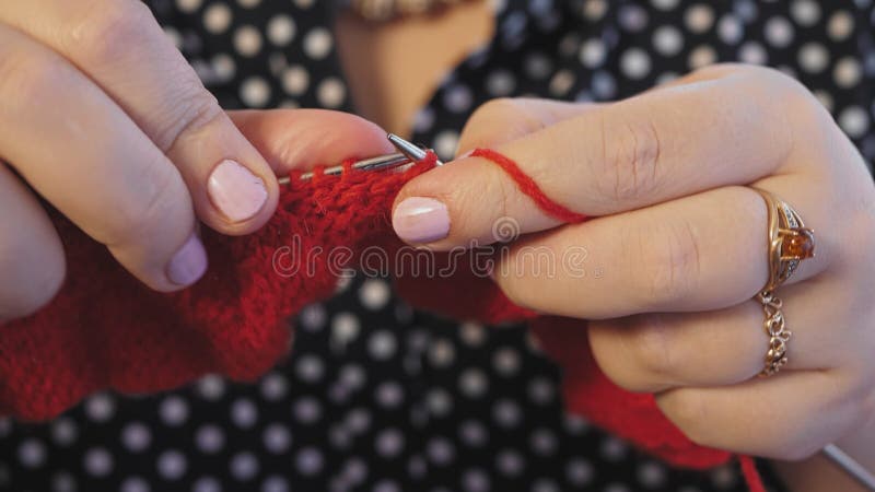 Las manos de la mujer tejen agujas de punto de hilados rojos