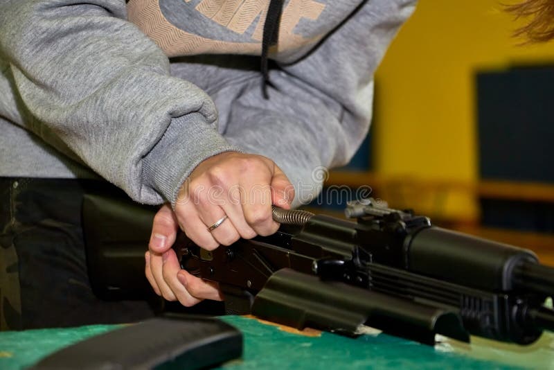 Las manos de los jóvenes están desmantelando un arma Adolescente recoge un rifle de asalto Kalashnikov sobre la mesa durante una. Las manos de los jóvenes están desmantelando un arma Adolescente colecciona un rifle de asalto Kalashnikov sobre la mesa durante una lección de guerra en una escuela rusa