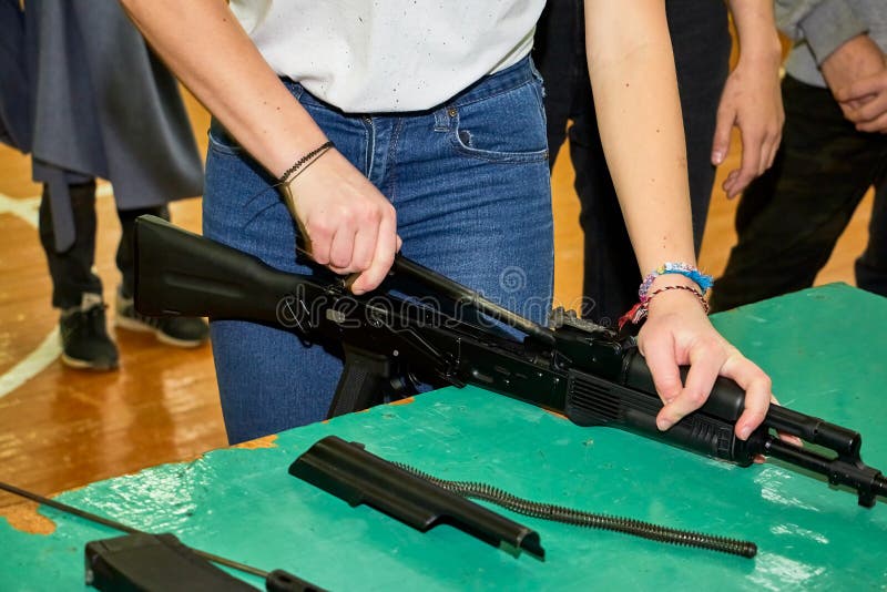 Las manos de los jóvenes están desmantelando un arma Adolescente recoge un rifle de asalto Kalashnikov sobre la mesa durante una fotografía de archivo