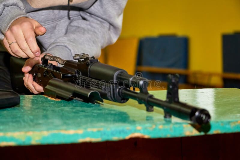 Las manos de los jóvenes están desmantelando un arma Adolescente recoge un rifle de asalto Kalashnikov sobre la mesa durante una foto de archivo libre de regalías