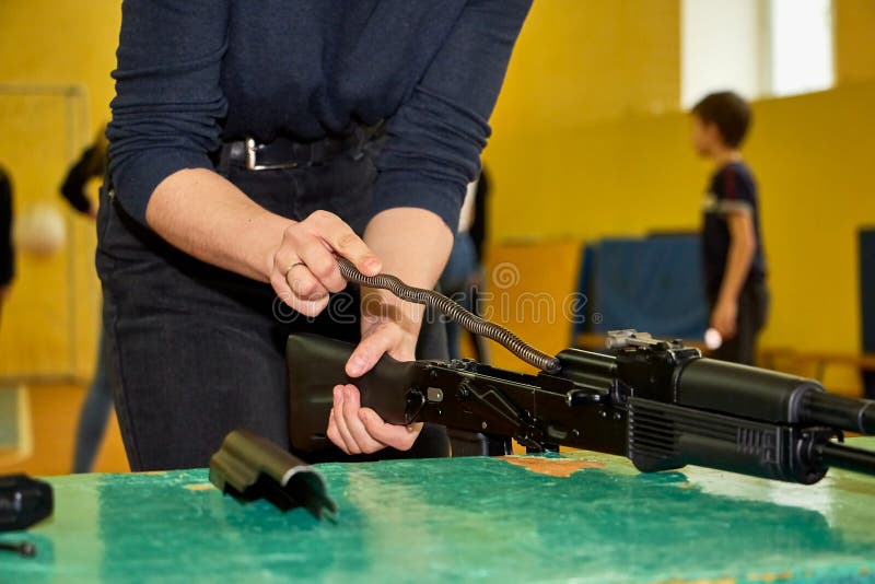 Las manos de los jóvenes están desmantelando un arma Adolescente recoge un rifle de asalto Kalashnikov sobre la mesa durante una imagen de archivo
