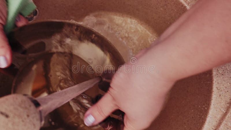 Las manos de las mujeres lavan las placas de vidrio en el fregadero con espuma bajo el agua