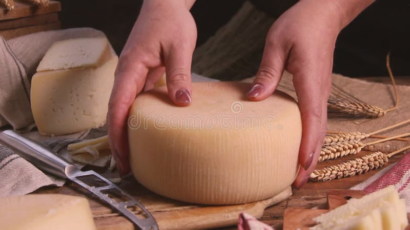 Las manos de las mujeres quitan la rueda del queso fresco casero cerca