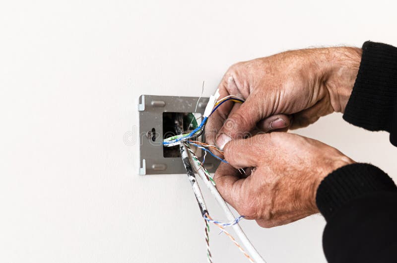 Las manos de un anciano montan una rosette en una pared blanca. reparación del apartamento. internet