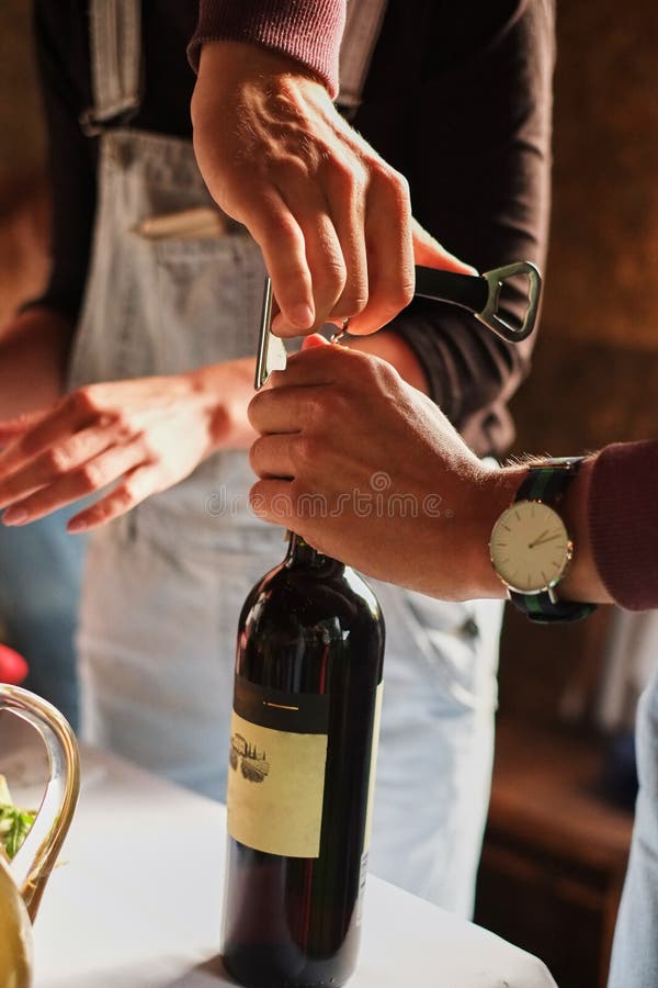 Las manos del hombre joven abren una botella de vino en un partido fotos de archivo Las manos del hombre joven abren una botella de vino en un partido fotos de archivo
