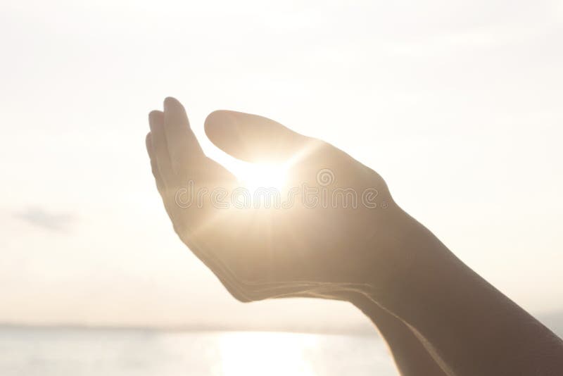 Las manos del ` s de la mujer llevan a cabo el sol y su energía