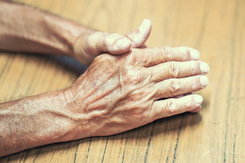 Las manos del viejo hombre en la tabla imágenes de archivo libres de regalías Las manos del viejo hombre en la tabla imágenes de archivo libres de regalías