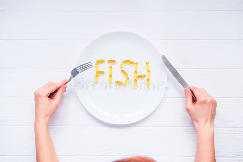 Las manos femeninas de la visión superior que sostienen el cuchillo y la bifurcación debajo de la placa redonda con los pescados imagenes de archivo Las manos femeninas de la visión superior que sostienen el cuchillo y la bifurcación debajo de la placa redonda con los pescados imagenes de archivo
