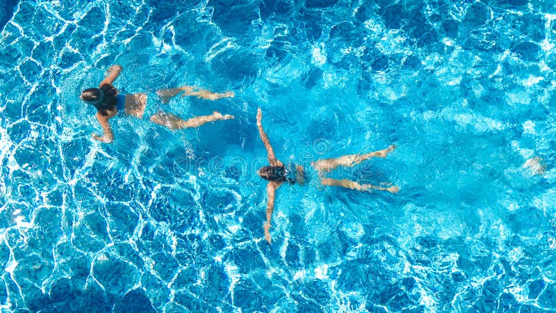 Las muchachas activas en la opinión aérea del abejón del agua de la piscina desde arriba, los niños nadan, los niños se divierten fotografía de archivo libre de regalías Las muchachas activas en la opinión aérea del abejón del agua de la piscina desde arriba, los niños nadan, los niños se divierten fotografía de archivo libre de regalías
