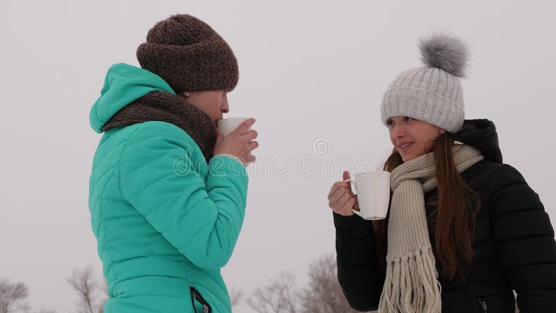 Las muchachas congeladas en bebidas calientes que hablan y de consumiciones frías de los vidrios ríen la sonrisa imagenes de archivo